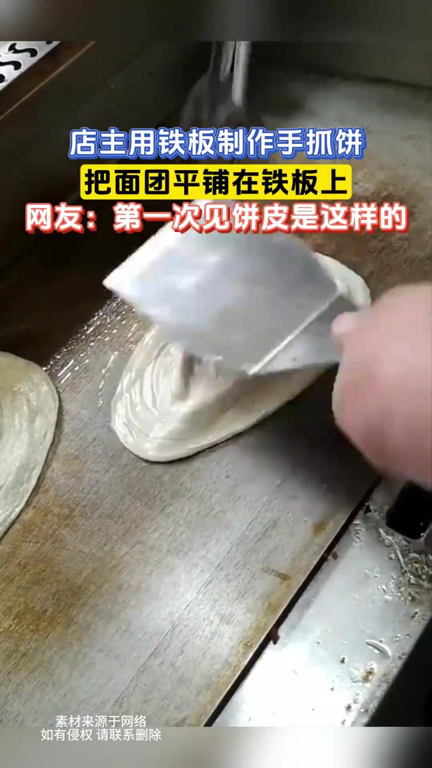 店主用铁板制作手抓饼，把面团平铺在铁板上