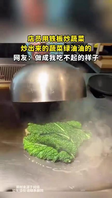 店员用铁板炒蔬菜，炒出来的蔬菜绿油油的