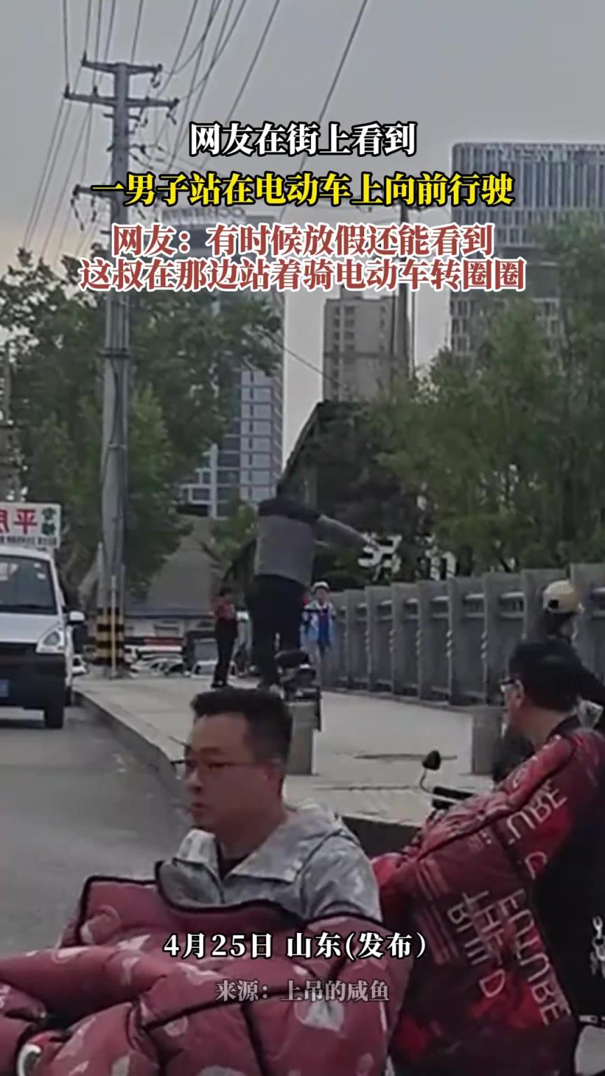 网友在街上看到一男子站在电动车上向前行驶！