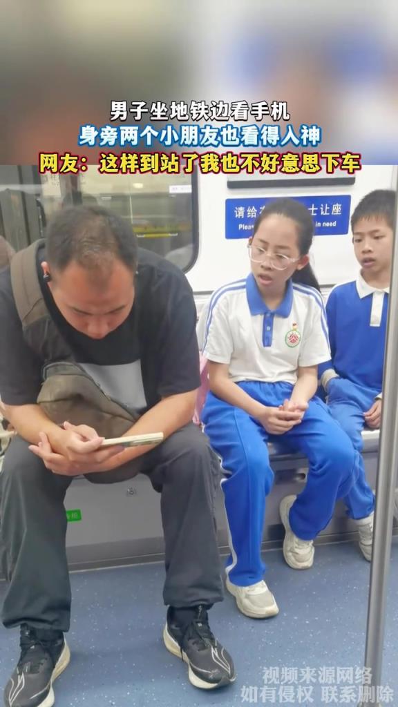 男子坐地铁边看手机 身旁两个小朋友也看得入神