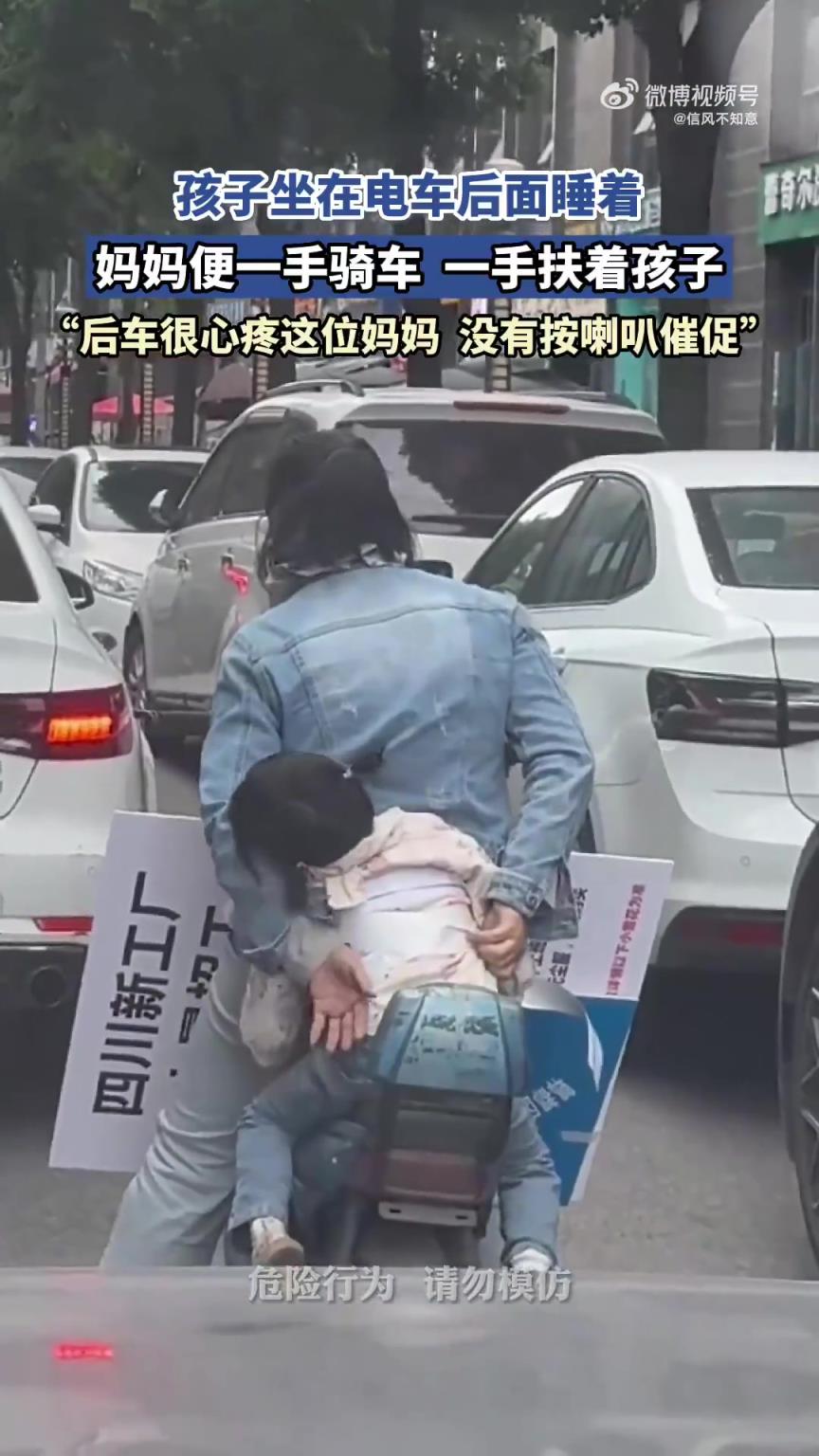 妈妈骑电车时一手扶睡着的孩子，单手操控令人捏把汗