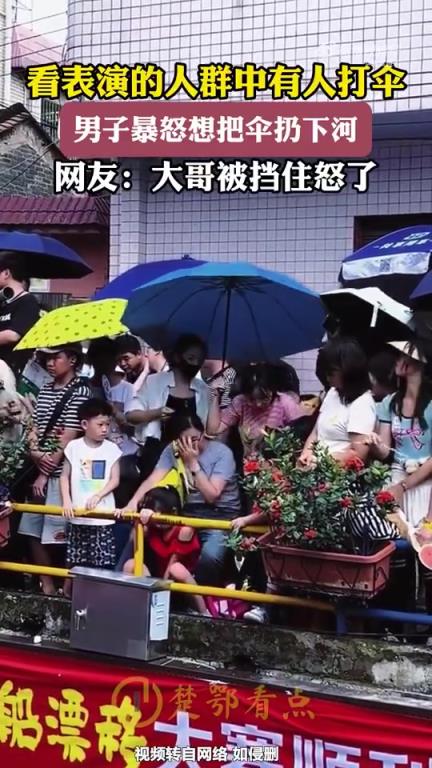 看表演人群中有人打伞，男子暴怒欲将伞扔下河