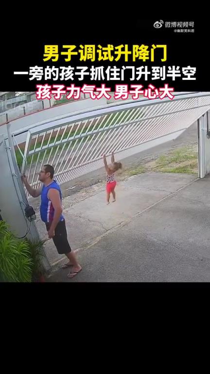 男子調試升降門，一旁孩子抓住門升到半空，孩子力氣大，男子心大