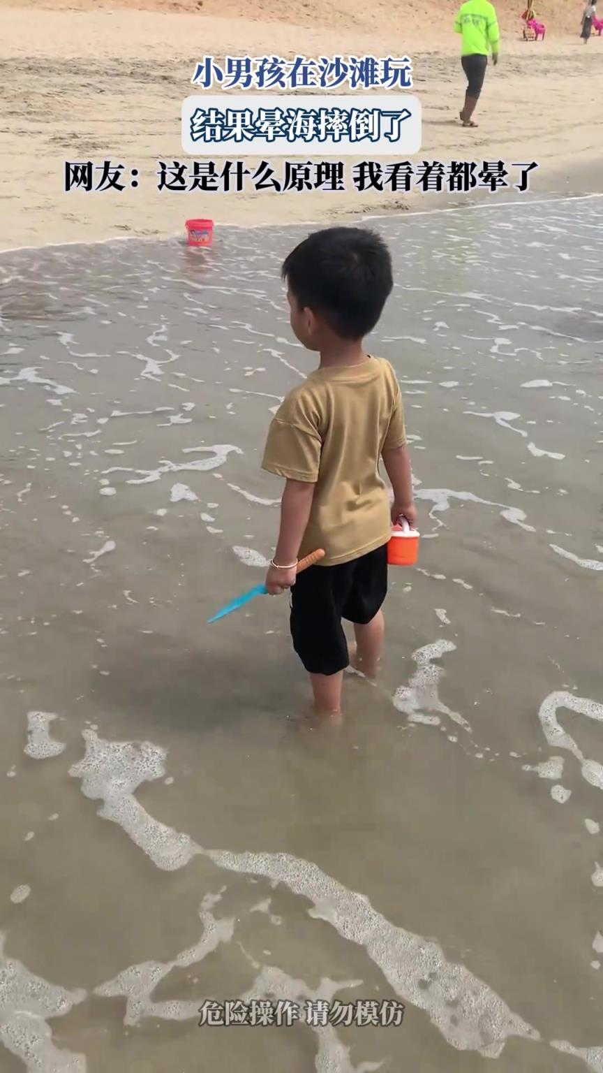 小男孩在沙滩玩，结果晕海摔倒了，网友：这是什么原理