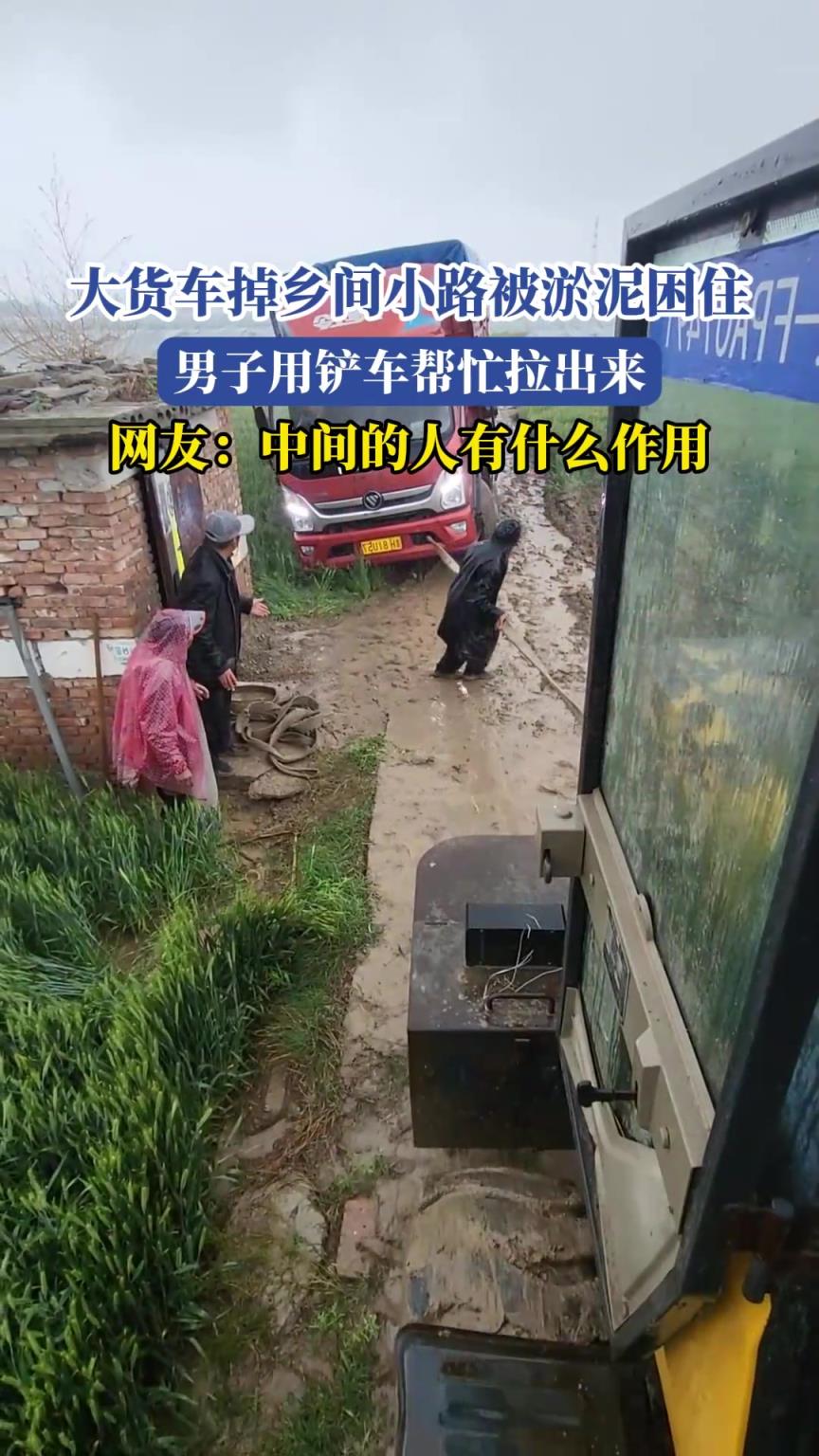 大貨車掉鄉(xiāng)間小路被淤泥困住，男子用鏟車幫忙拉出來