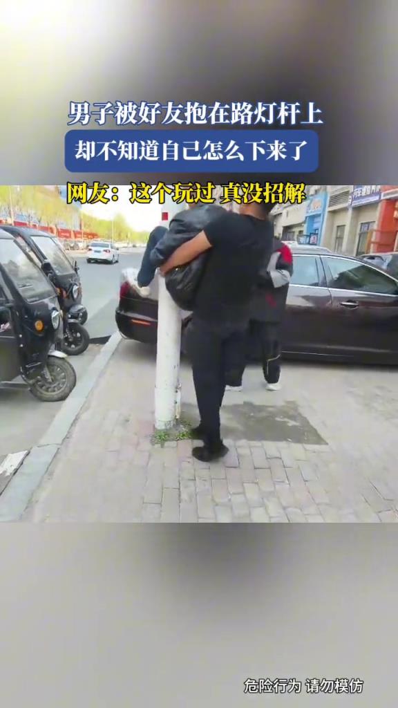 男子被好友抱在路燈桿上,卻不知道自己怎么下來(lái)了!