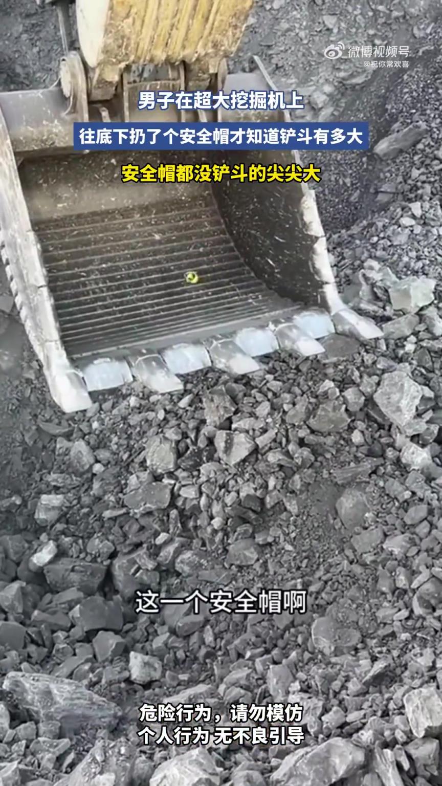 男子在超大挖掘机上，往底下扔了个安全帽才知道铲斗有多大！