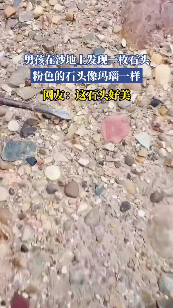 男孩在沙地上发现一枚石头，粉色的石头像玛瑙一样！