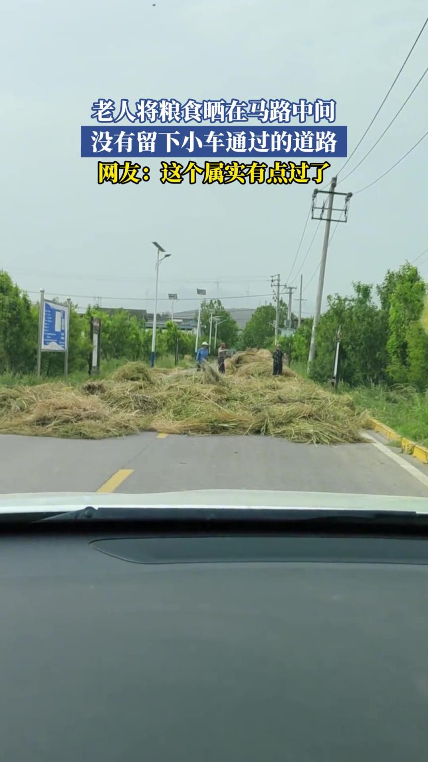 老人将粮食晒在马路中间 没有留下小车通过的道路