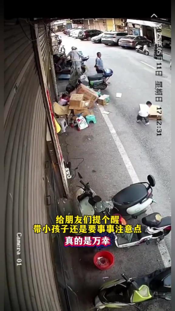 小孩钻进路边纸箱里玩耍被车压脚，所幸无大碍！