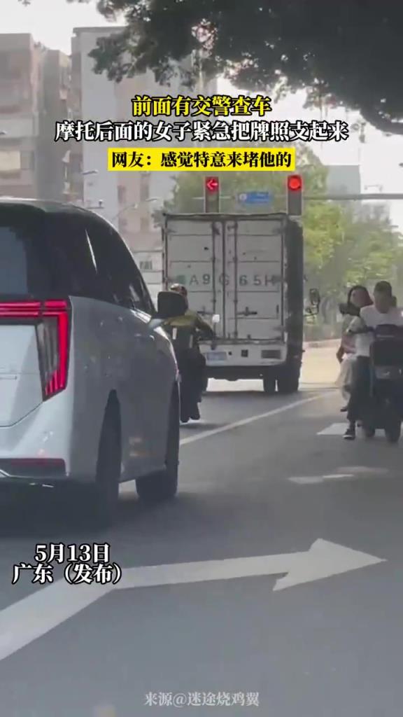 前面有交警查车 摩托车后面的女子紧急把牌照支起来