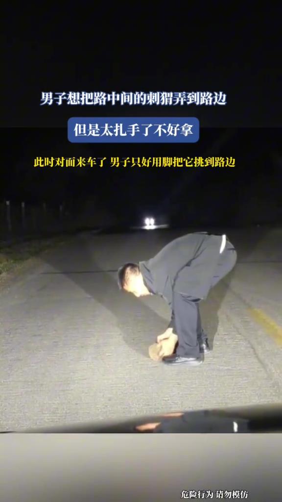 男子想把路中间的刺猬弄到路边,但是太扎手,于是只好用脚!