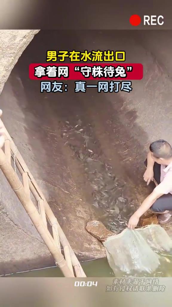 男子在水流出口，拿着网“守株待兔”
