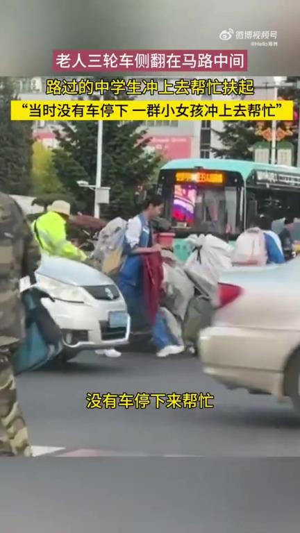 老人三轮车侧翻在马路中间，路过的中学生冲上去帮忙扶起