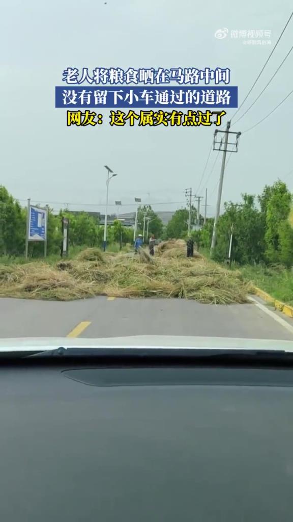 老人将粮食晒在马路中间，没有留下小车通过的道路！