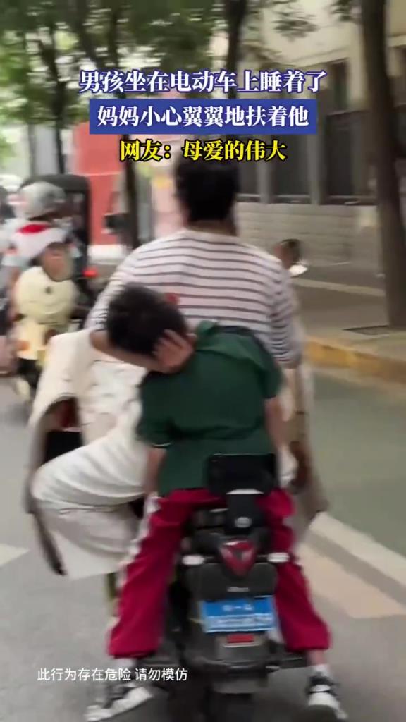 男孩坐在電動車上睡著了 媽媽小心翼翼地扶著他