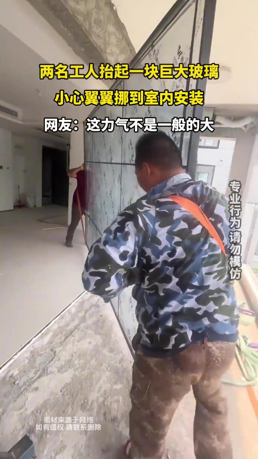 两名工人抬起一块巨大玻璃，小心翼翼挪到室内安装