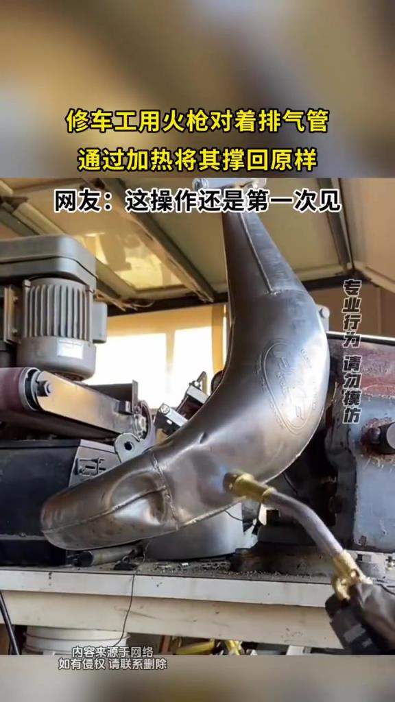 修车工用火枪对着排气管，通过加热将其撑回原样