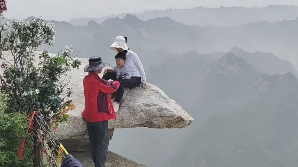 游客拍照打卡，拍摄者和大人，有绳索保护，小孩子没有任何保护