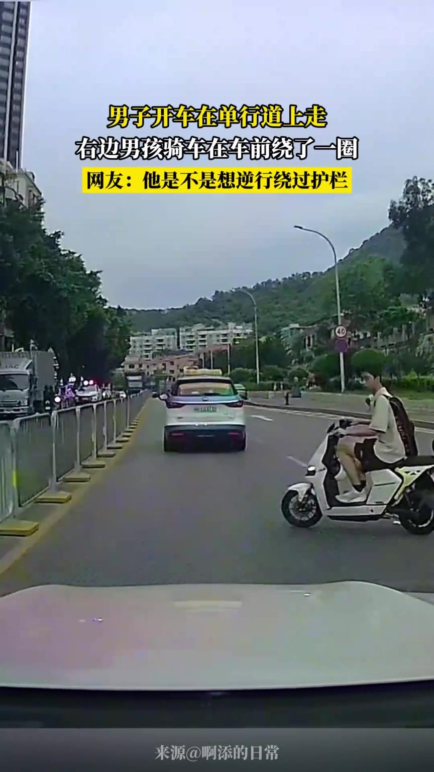 男子开车在单行道上走，右边男孩骑车在车前绕了一圈