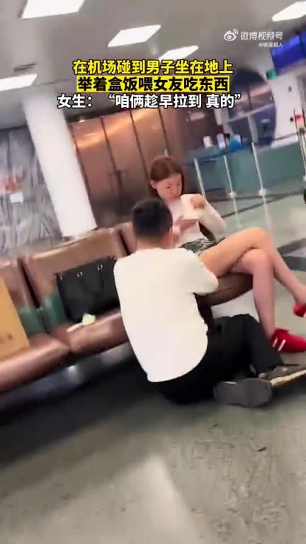 機(jī)場一幕：男子坐地舉盒飯喂女友進(jìn)食