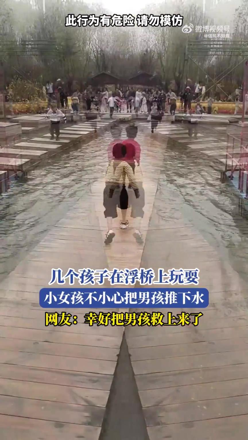 几个孩子浮桥上玩耍，小女孩不慎将男孩推下水