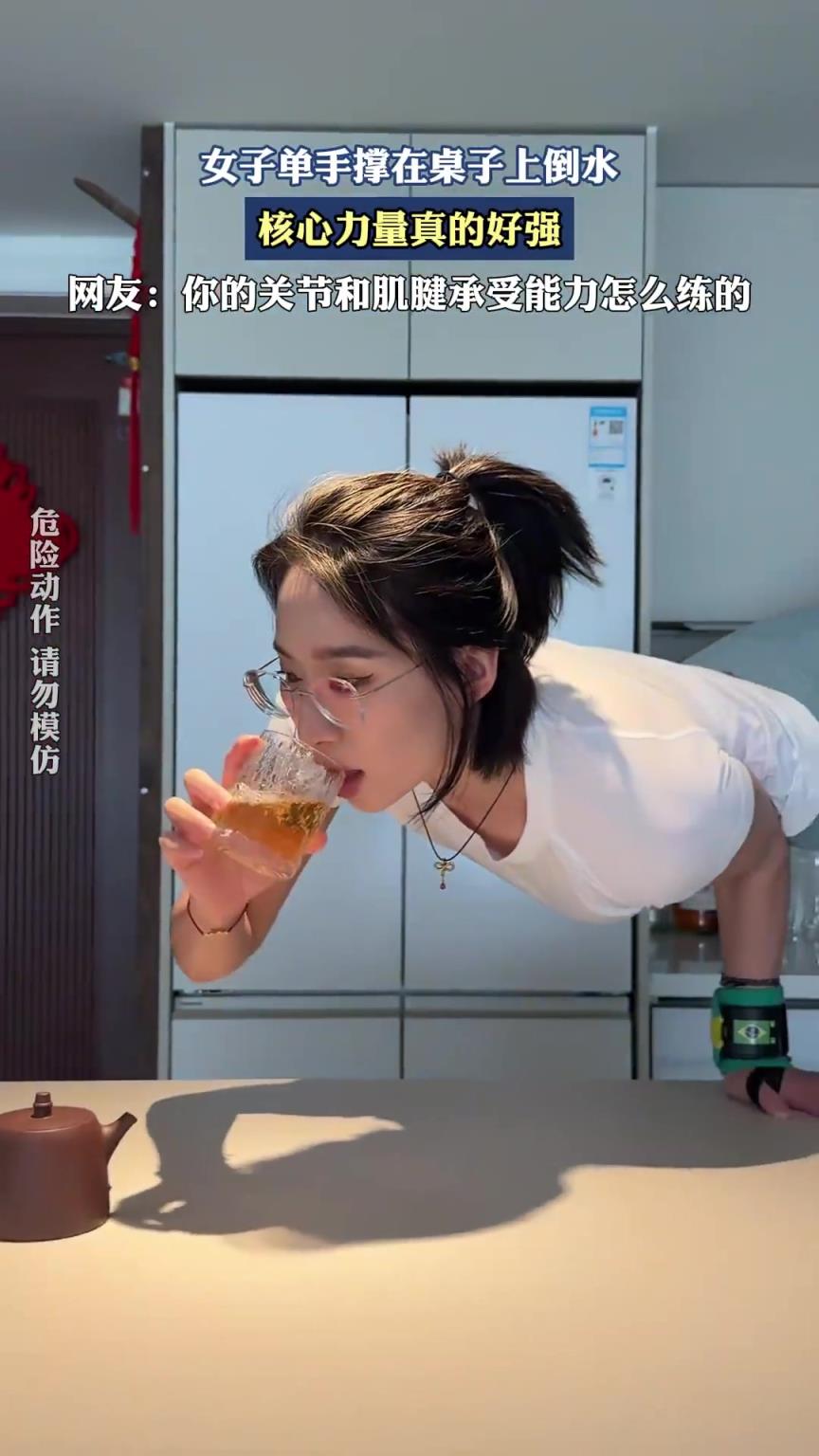 女子单手撑在桌子上倒水，核心力量真的好强。