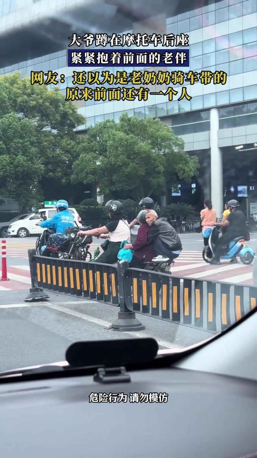 大爺蹲在摩托車后座，緊緊抱著前面的老伴