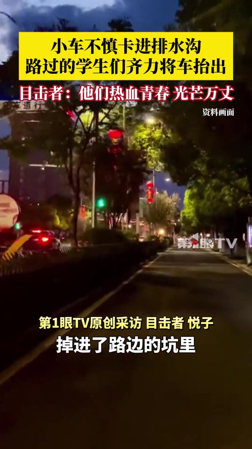 小車不慎卡進(jìn)排水溝，路過(guò)的學(xué)生們喊著號(hào)子齊力將車抬出