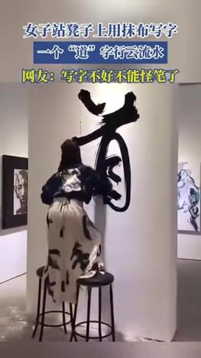 女子站凳子上用抹布寫字，一個“道”字行云流水