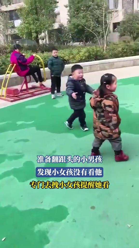 准备翻跟头的小男孩 发现小女孩没有看他 专门去拽小女孩提醒她看