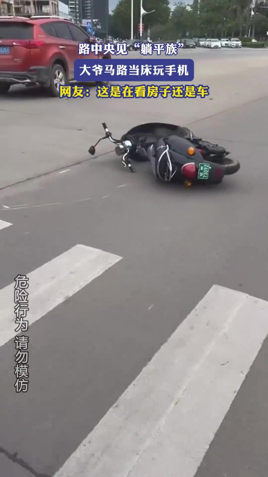 路中央見躺平族，大爺馬路當(dāng)床玩手機(jī)，網(wǎng)友：這是在看房子還是車