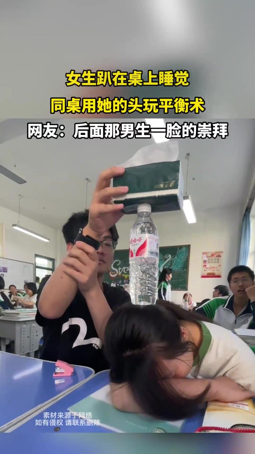 女生趴在桌上睡覺，同桌用她的頭玩平衡術(shù)