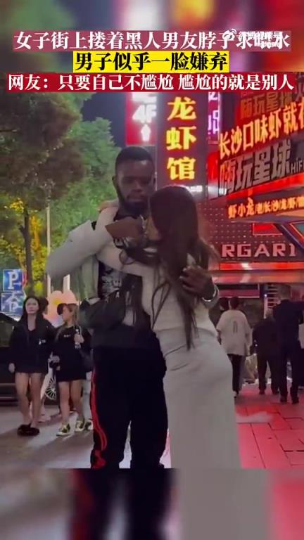 女子街上摟著黑人男友脖子求喂水，男子似乎一臉嫌棄
