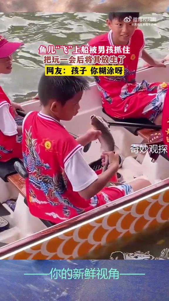 魚兒“飛”上船被男孩抓住，把玩一會(huì)后將其放生了