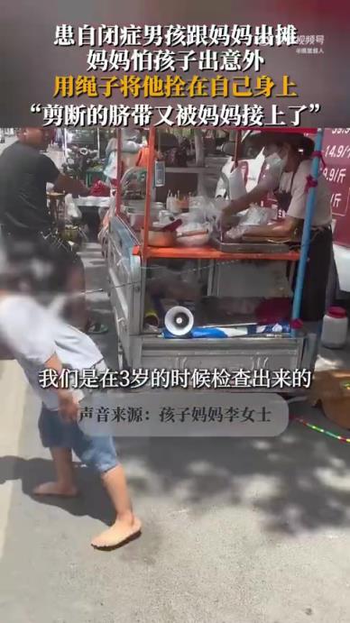 患自闭症男孩跟妈妈出摊，妈妈怕孩子出意外，用绳子将他拴在身上