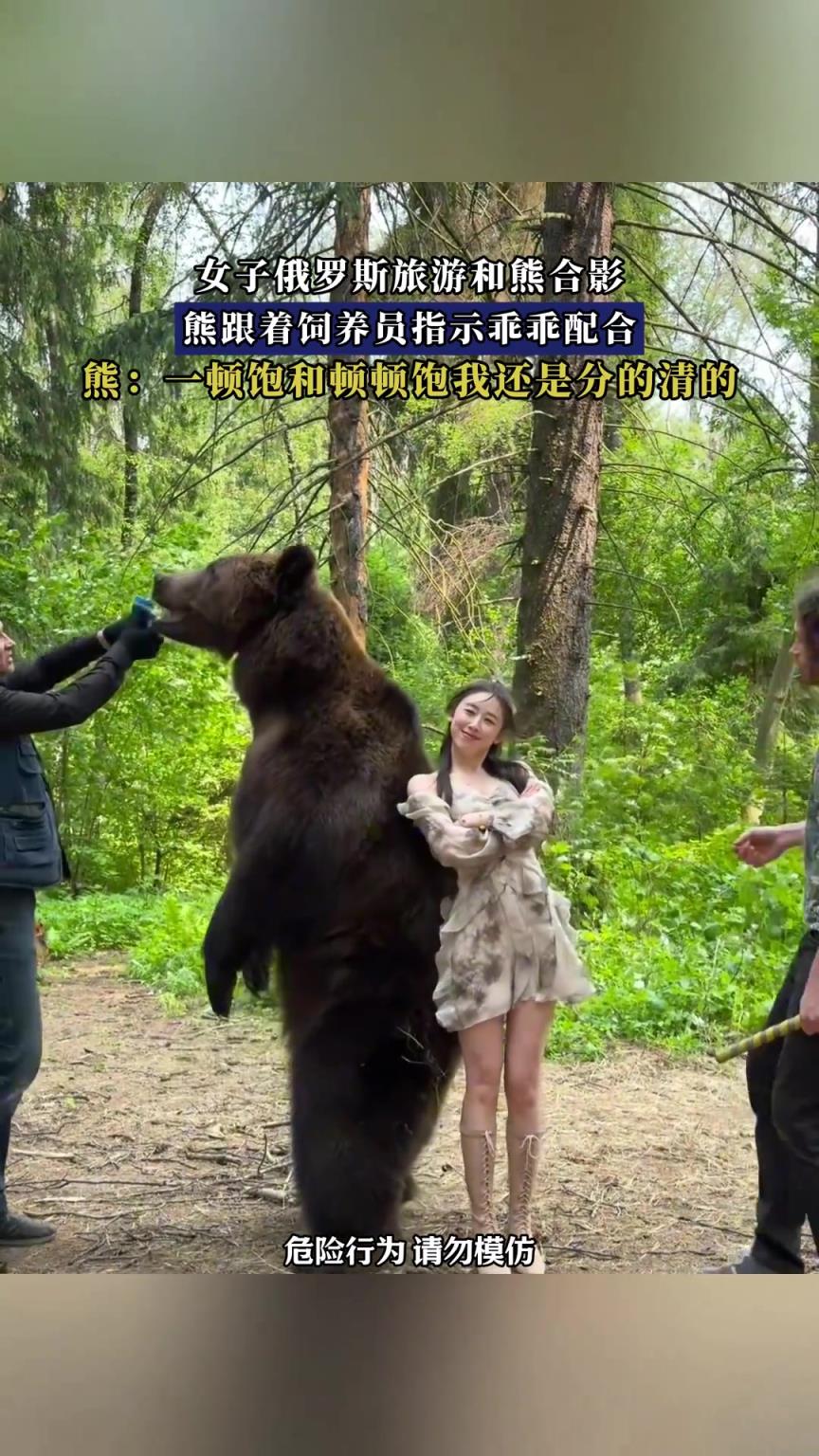 女子俄羅斯旅游和熊合影，熊跟著飼養(yǎng)員指示乖乖配合