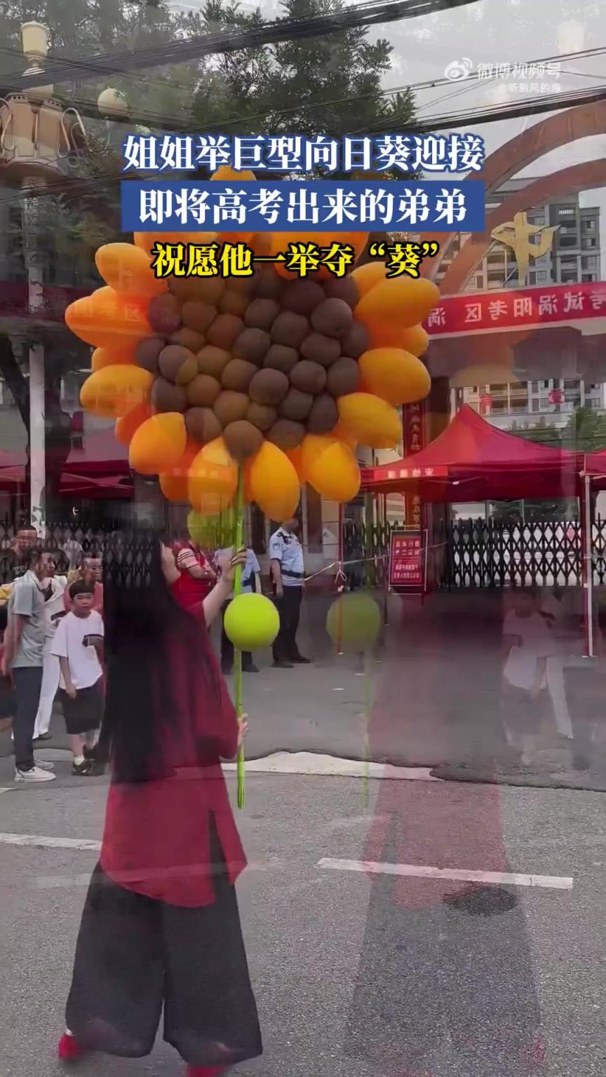 姐姐舉巨型向日葵迎接即將高考出來的弟弟，祝愿他一舉奪“葵”！