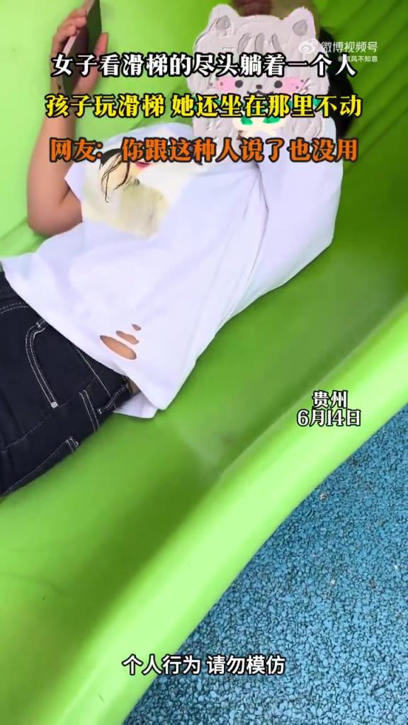 女子看滑梯的尽头躺着一个人 孩子玩滑梯 她还坐在那里不动