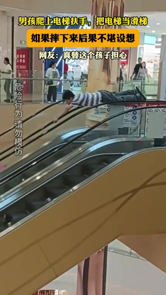男孩爬上电梯扶手,把电梯当滑梯,如果摔下来后果不堪设!