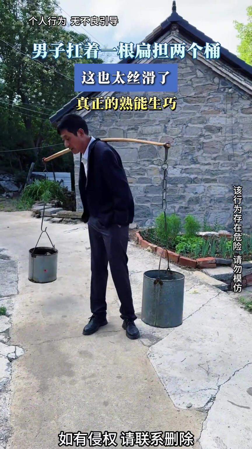 男子扛着一根扁担两个桶，这也太丝滑了，真正的熟能生巧